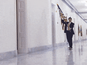 Stephen Colbert waves the American flag while rollerskating down a hallway.